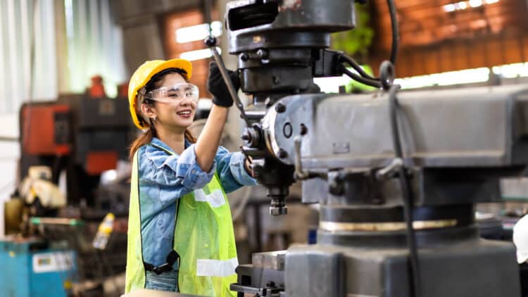 Worker wearing safety goggles control lathe machine