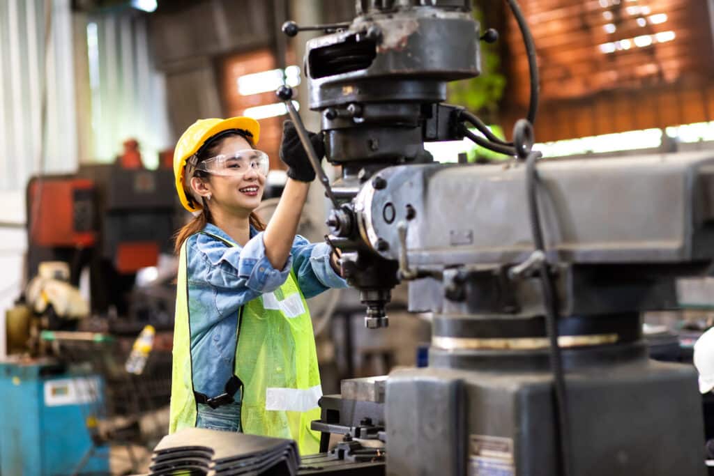 Worker wearing safety goggles control lathe machine