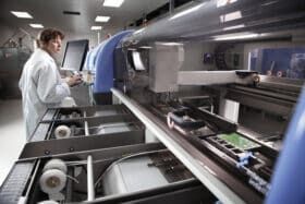 Person in a lab coat using manufacturing machinery