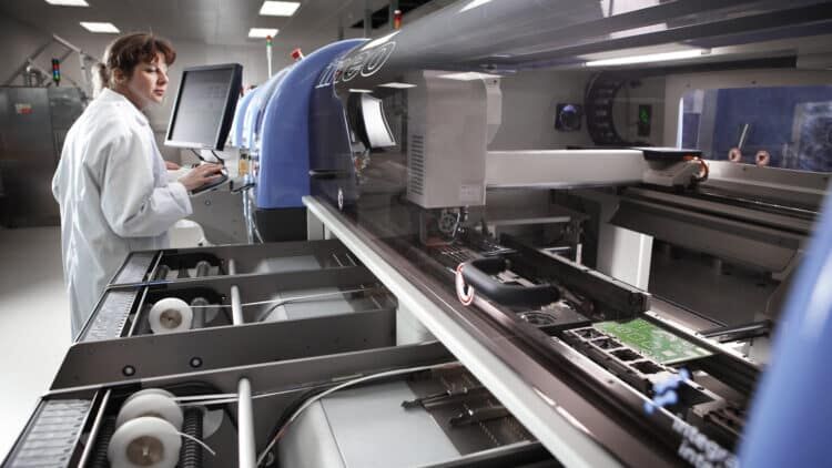 Person in a lab coat using manufacturing machinery