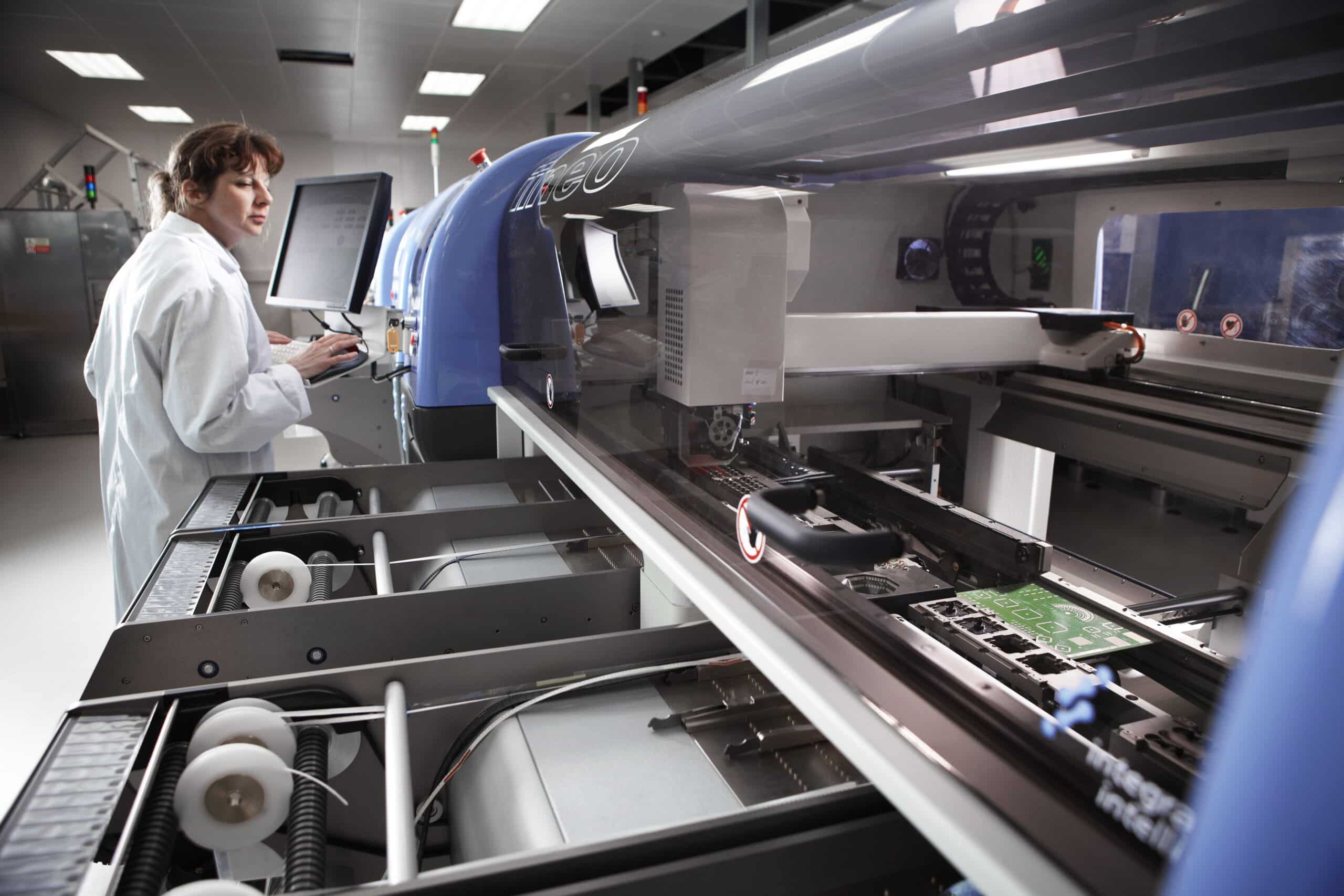 Person in a lab coat using manufacturing machinery