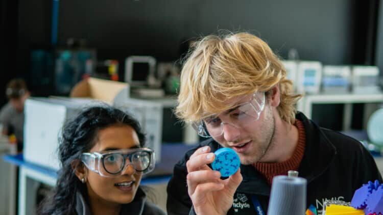 Two young people, male and female observing some brightly coloured objects Both wearing safety glasses